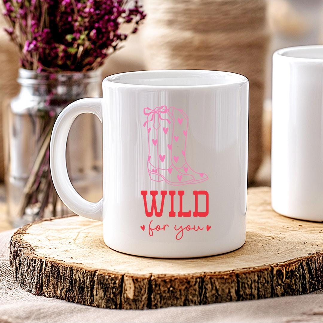 Weiße Keramiktasse mit pinkem Cowboy-Stiefel-Design und Herz-Details sowie rotem Schriftzug „Wild for You“.